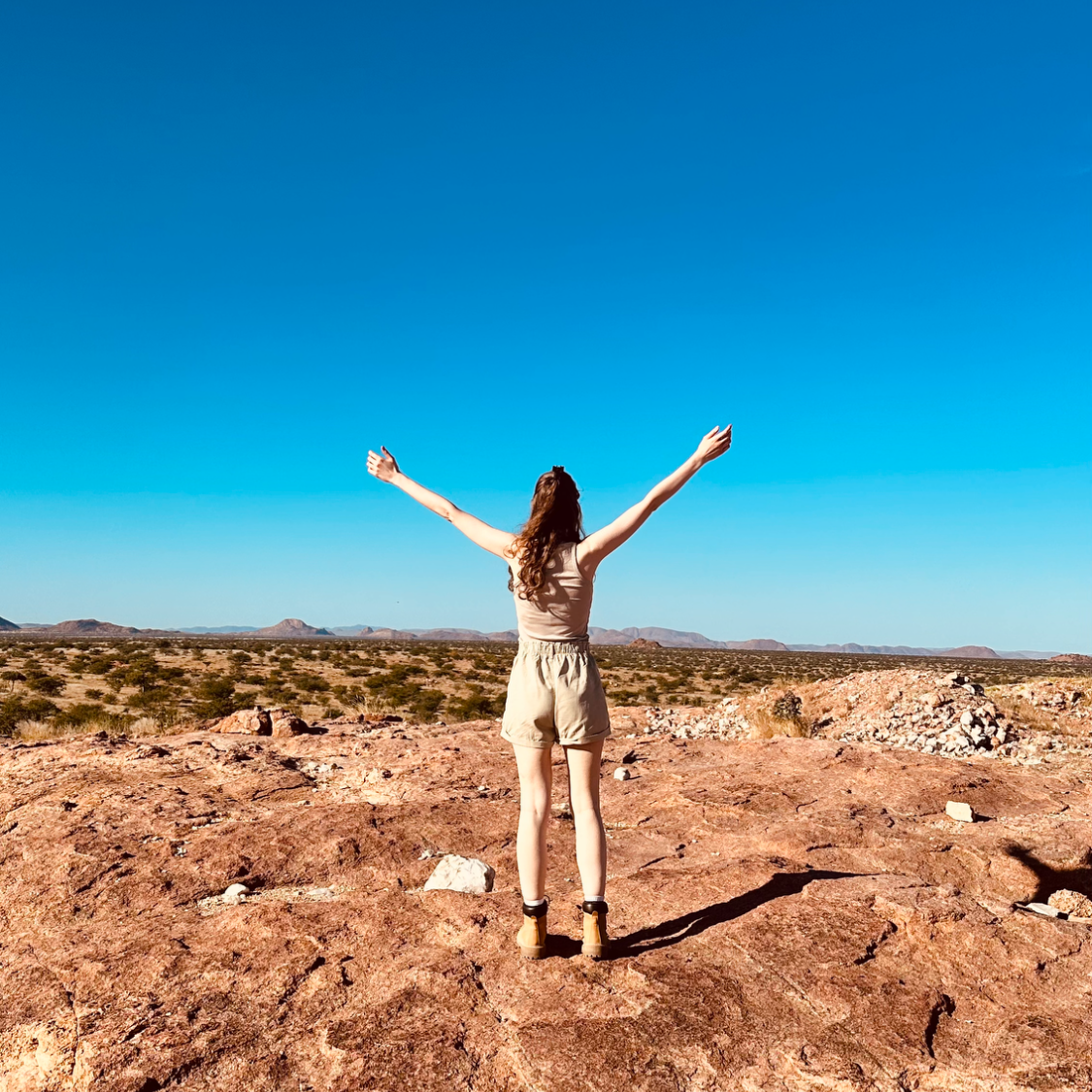Ich stehe auf einem Plateau über der Savanne in Namibia.